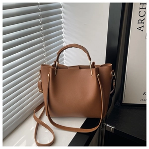 Close-up of caramel brown lychee leather texture and metal handle joints on tote bag