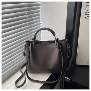 Detailed view of dark brown lychee textured tote bag with elegant golden metal hardware