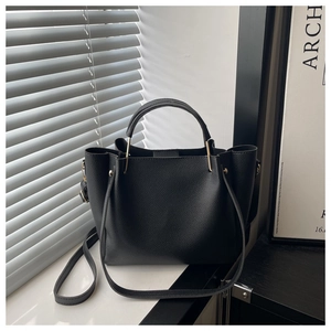 Detail of black litchi grain leather tote with golden hardware and double handles