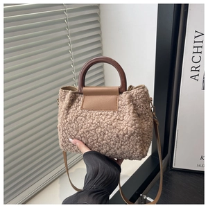 Detail of soft teddy plush shoulder bag featuring round brown resin handles and slim strap