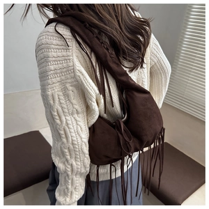 Detail of dark brown suede tassel bag with braided shoulder strap on model