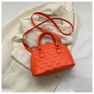 Detalle de bolso naranja con textura de tablero de ajedrez sobre blazer blanco
