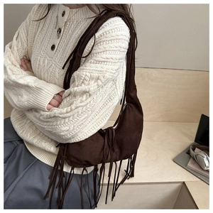 Detail of dark brown suede hobo bag featuring long decorative tassels and metal zipper