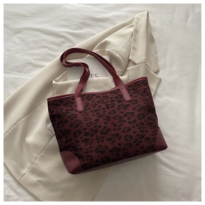 Macro shot of burgundy leopard print tote bag with suede texture and leather handles