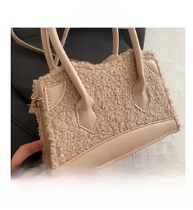 Detail of beige faux shearling handbag showing leather trim and gold metal buckle