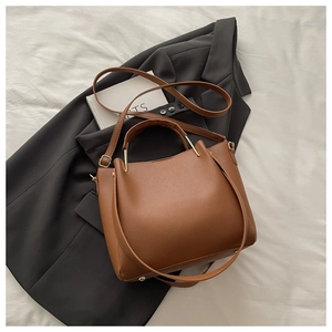 Detail of caramel brown lychee leather handbag with gold metal hardware and adjustable strap