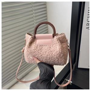 Detail of pink sherpa bucket bag with brown circular handle and leather crossbody strap