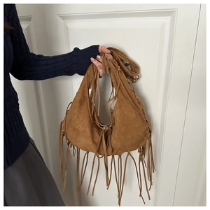 Detail of dark brown suede half-moon bag featuring long fringe tassels and retro style