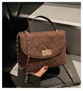 Detailed view of brown quilted handbag with gold turn-lock and chain strap on book base