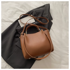 Detail of brown lychee grain leather handbag with stylish gold metal ring handles