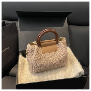 Close-up of beige fleece bucket bag with brown leather flap and round resin handle