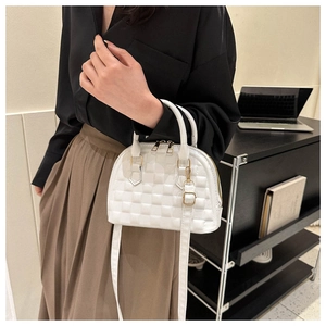 Detalle del bolso de concha blanco con textura de cuadros y herrajes dorados en modelo