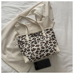 Detailed close-up of leopard print tote bag with cream leather trim and metal rivets
