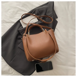 Detail of brown litchi pattern leather tote showing gold metal hardware and texture