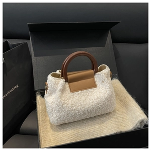 Detail of white sherpa bucket bag with brown handles in a premium black gift box