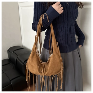 Detailed macro view of brown suede tote bag with long tassel fringe and crescent shape