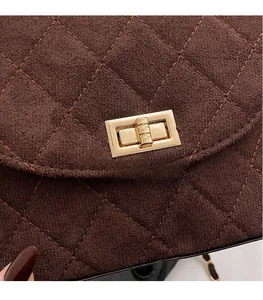 Detail of dark brown quilted suede texture and golden twist lock on a small crossbody bag