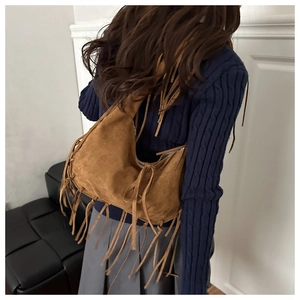 Detail of bohemian brown suede shoulder bag with long fringes shown on a model