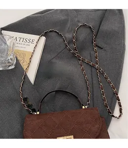 Top view of brown quilted crossbody bag with golden chain strap on a grey blazer