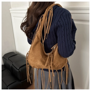 Detailed view of a brown suede hobo bag with long fringes and bohemian aesthetic