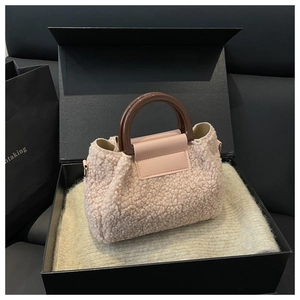 Pink shearling bucket bag with leather flap and dark brown handle in a premium gift box