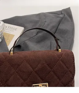 Close-up of brown quilted suede handbag with vintage gold hardware and soft texture