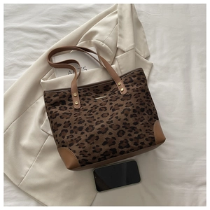 Detail of leopard print tote bag with brown leather straps and gold metal logo plaque