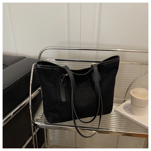 Detail of minimalist black suede tote bag showing long adjustable shoulder strap and buckle
