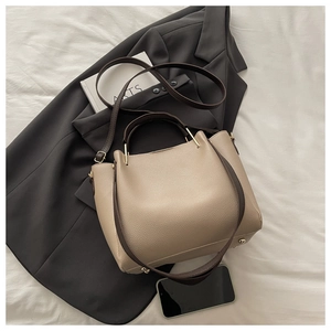 Flat lay of khaki lychee leather tote bag with dark brown straps and metal hardware