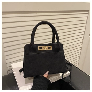 Gros plan du sac à main en cuir mat noir avec fermoir doré et doubles poignées rondes