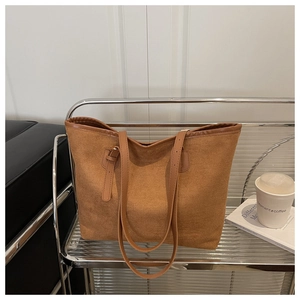 Detailed macro view of brown suede tote bag with slim leather straps and trim edges