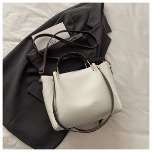 Detail of white lychee leather texture and brown handle on a stylish tote bag
