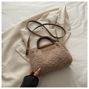 Detail of teddy fleece bucket bag with dark wooden circular handle and leather strap