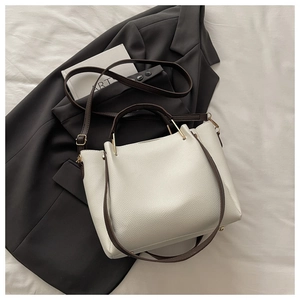 Detailed close-up of lychee grain leather texture and metallic gold hardware on tote bag