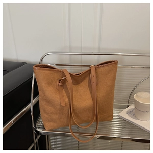 Detail of minimalist brown tote bag with textured fabric and adjustable strap on a shelf