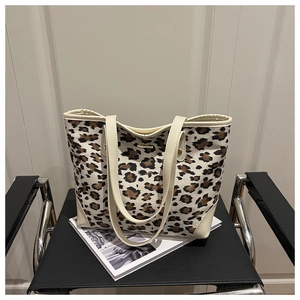 Close-up of leopard print tote bag with metal logo on a modern black designer chair
