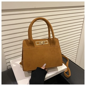 Détail d'un sac trapèze marron mat avec fermoir doré tournant et doubles poignées