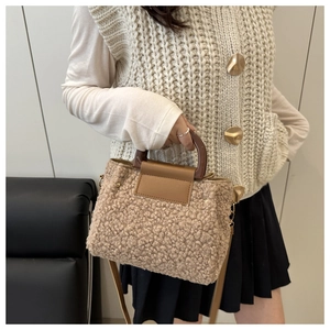 Close-up of brown faux shearling handbag with wooden handle and adjustable strap