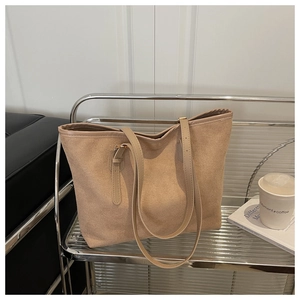Detail of minimalist tote bag in apricot suede and PU leather on a modern shelf