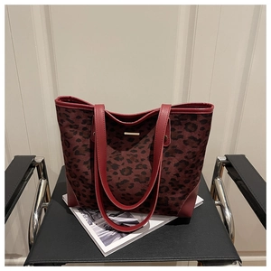 Detail of leopard print tote bag with red leather trim and gold metal accessory