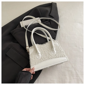 Gros plan du sac en peluche blanc avec garniture en similicuir et détails métalliques