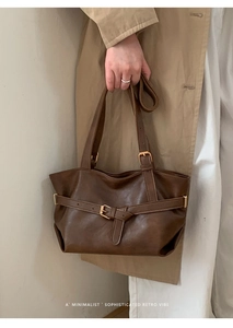 Dettaglio della borsa tote vintage in pelle marrone con fibbia dorata e trama minimalista