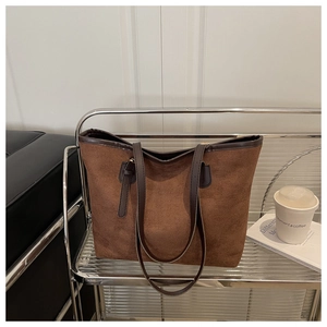 Detail of caramel suede tote bag with coffee leather trim on a modern glass shelf
