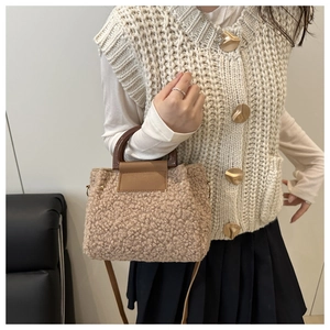Detail of soft beige faux shearling bucket bag with wood-grain handle and leather flap