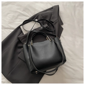 Macro detail of black lychee texture leather handbag with elegant gold hardware accents