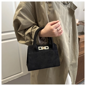 Dettaglio di una borsa vintage in pelle scamosciata nera con chiusura a scatto dorata