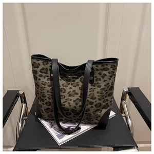 Detail of leopard print tote bag with black leather trim and gold metal logo on a chair