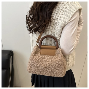 Close-up of a plush faux fur bucket bag with brown resin handle and leather strap detail