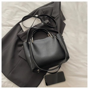 Detail of black lychee grain leather tote bag with gold hardware and protective rivets