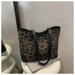 Detail of leopard print tote bag with black leather reinforced corners and metal hardware